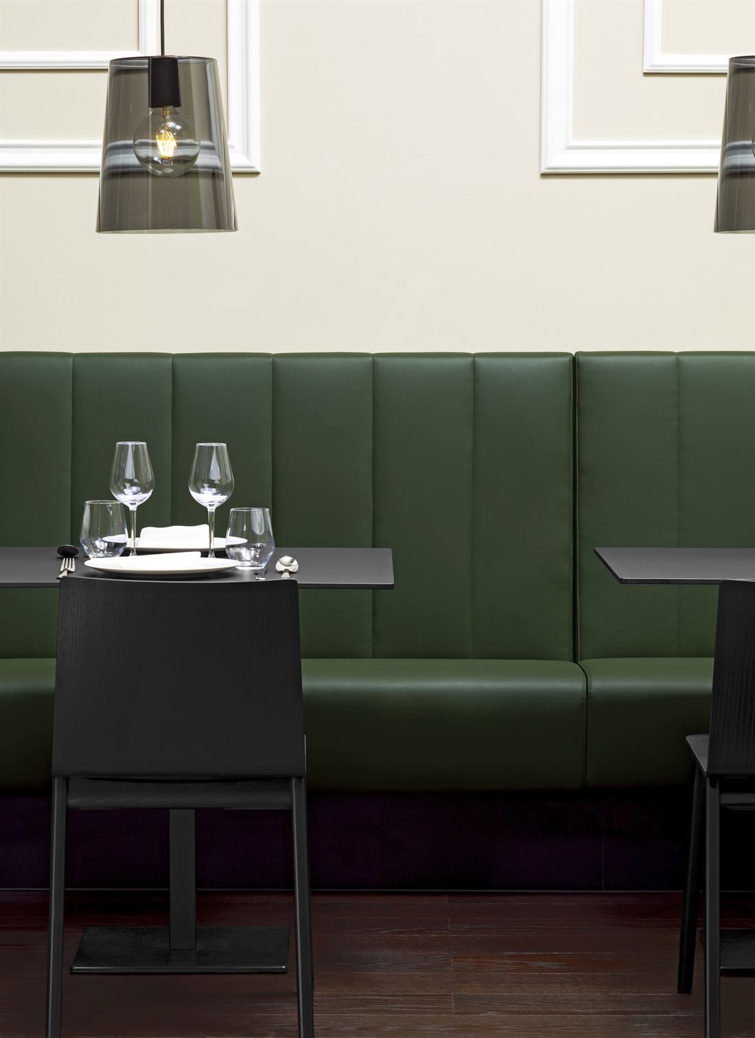 Grüne Lederbank mit schwarzen Stühlen und Tischen im Restaurant
